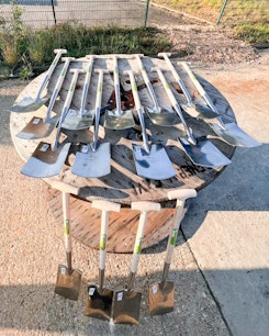 Spaten Spatenstich 2025 Fichtenau mehrere Spaten liegen auf einer Leertrommel aus Holz